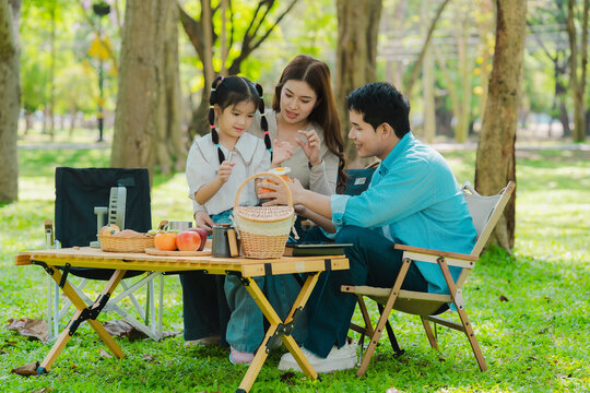 A family of three from Asia enjoyed using their laptops in the park and also enjoyed a picnic together in the park.