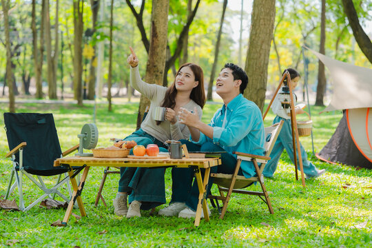 A family of three from Asia enjoyed using their laptops in the park and also enjoyed a picnic together in the park.