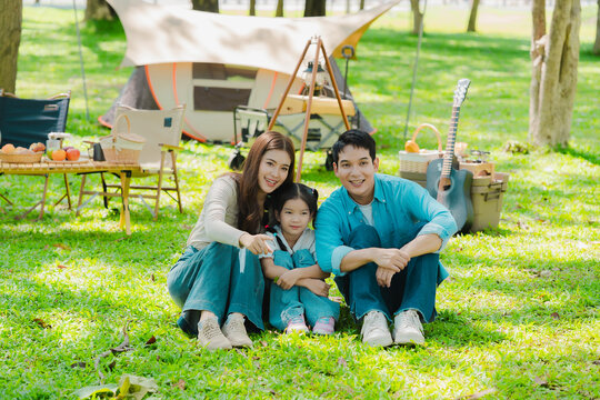 A family of three from Asia enjoyed using their laptops in the park and also enjoyed a picnic together in the park.