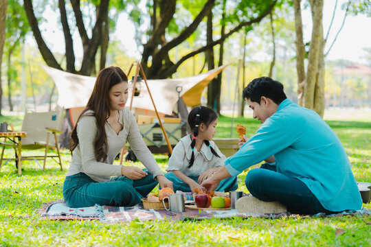 A family of three from Asia enjoyed using their laptops in the park and also enjoyed a picnic together in the park.