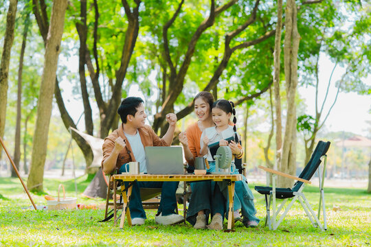 A family of three from Asia enjoyed using their laptops in the park and also enjoyed a picnic together in the park.