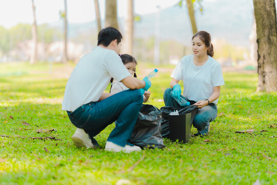 Environmental conservation concept: A cute little girl and her parents are picking up trash in the park. A family of volunteers is collecting trash in the forest. Environmental conservation concept.