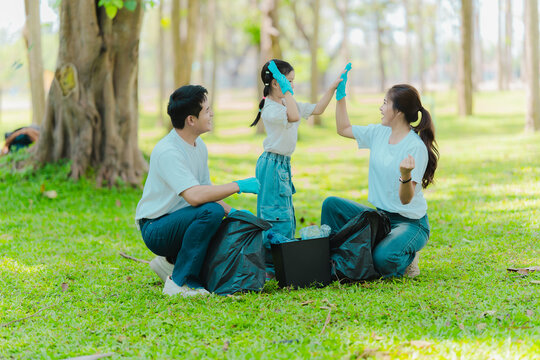 Environmental conservation concept: A cute little girl and her parents are picking up trash in the park. A family of volunteers is collecting trash in the forest. Environmental conservation concept.