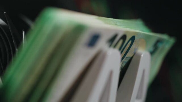 Stack of euro banknotes processed in modern counting device with speed and precision. Concept economic activity and business growth.
