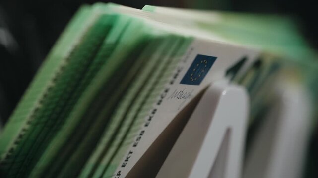 Close-up sequence of euro banknotes being organized in a cash register, showcasing the detailed design and vibrant colors of the currency in a retail environment