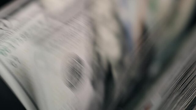 Close-up financial scene with money counting machine processing hundred dollar notes. Concept corporate finance and accounting workflow.
