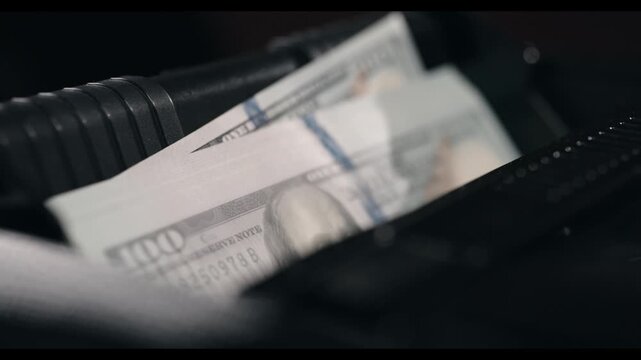 Close-up sequence of cash being placed into a black briefcase, showcasing the detailed texture of the money and the briefcase's interior design in a dimly lit environment