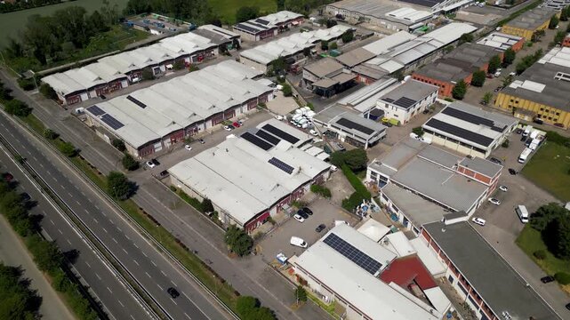 Industrial Park Aerial View: An aerial perspective showcases a sprawling industrial park with rows of warehouses, office buildings, and solar panels, bordering a major highway.