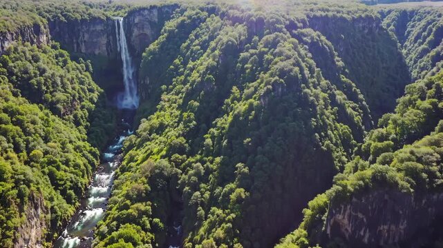 Breathtaking aerial view of stunning waterfall in lush green mountains. Nature showcases vibrant landscape with flowing river below. Serenity and beauty define this enchanting scenery.