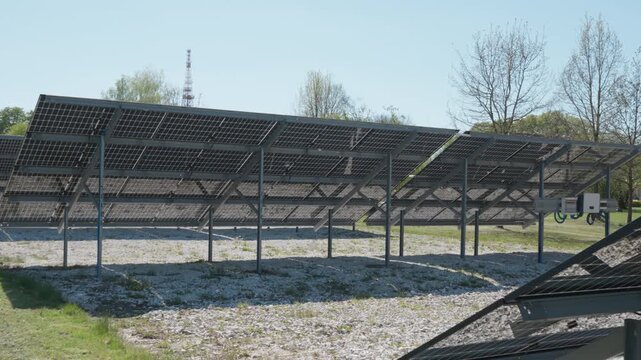 Bifacial solar panels array installed on white gravel to reflect sunlight onto back side. Renewable energy farm with photovoltaic modules generating clean electricity on sunny day outdoors.