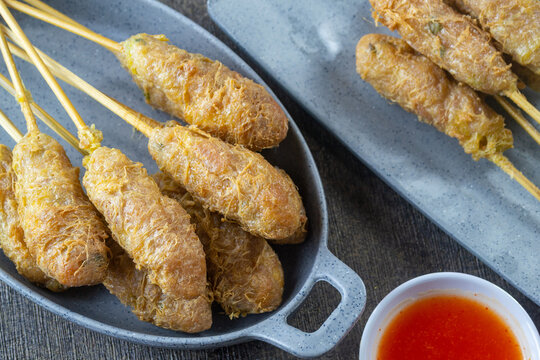 Indonesian street food sempol ayam served on a grey plate with spicy chili dipping sauce, deep fried chicken skewers coated with egg