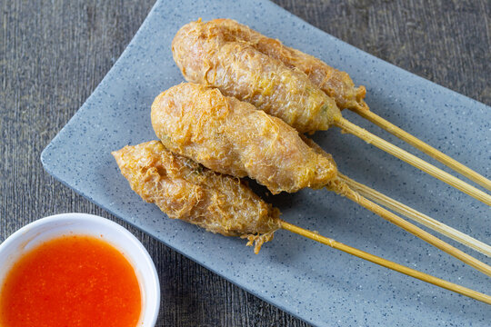 Indonesian street food sempol ayam served on a grey plate with spicy chili dipping sauce, deep fried chicken skewers coated with egg