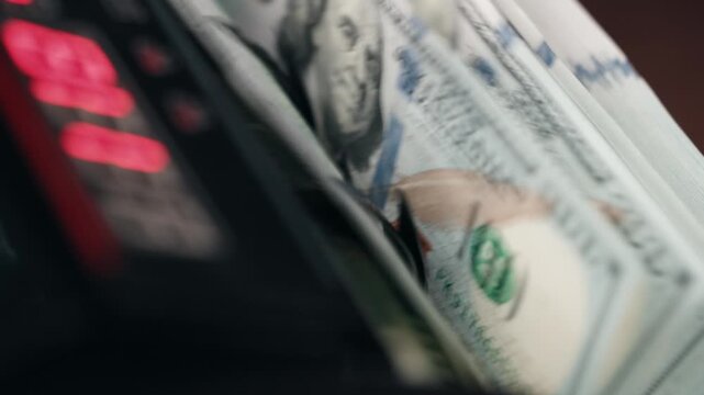 Money counting machine handling stack of hundred dollar notes in modern financial environment. Concept investments and capital management.
