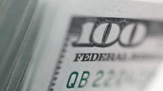 Close-up of currency counting machine counting US 100 dollar banknotes with high speed precision. Concept finance automation and business efficiency.
