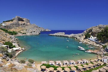 Obraz premium Golden sandy beach on Rhodes, Greece, with gentle waves and blue horizon, ideal holiday destination.
