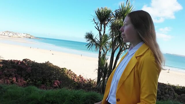 A woman walks on the evening seaside wearing yellow jacket