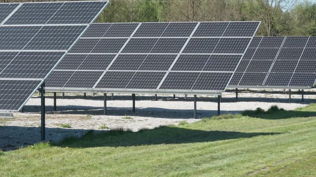 Rows of bifacial photovoltaic solar panels on ground mount racking system. Renewable energy farm with double-sided modules on white gravel to maximize albedo and power generation yield.