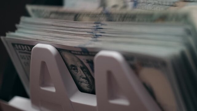 Close-up view of stacks of U.S. currency in a white money holder, showcasing the detailed texture and design of the banknotes in a well-lit indoor setting