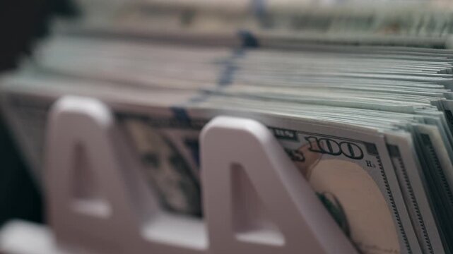 Automatic cash counting machine processing stack of hundred dollar bills in close-up with motion blur. Concept banking technology and money management.
