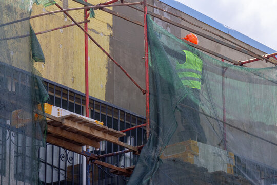 Construction worker on scaffolding performing wall insulation and facade renovation of a building