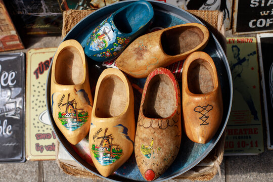 Collection of vintage wooden clogs displayed in a round metal tray at an antique market stall