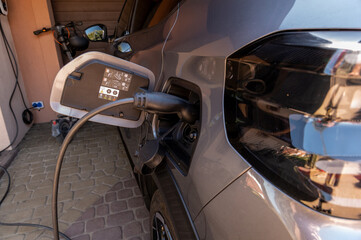 Electric vehicle charging port close-up detail Description: Detailed view of an electric car charging port with cable connected. Concept of alternative energy and eco-friendly transportation. © Micha