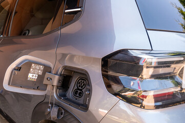 Modern electric car charging close-up with warm light Description: Close-up of an electric vehicle charging socket in warm natural light. Concept of future mobility and clean energy. © Micha