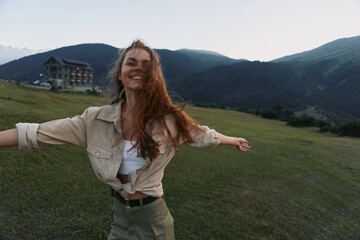 Naklejka premium Cheerful woman outdoors, embracing a sunlit moment in a green field, arms open, carefree smile, natural breeze, mountain backdrop, vibrant natural colors with warmth.