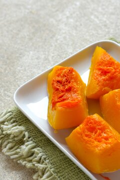 Close up slices of steamed pumpkin on a white plate, healthy steamed organic squash for a vegan diet, nutritious superfood snack. Labu kukus