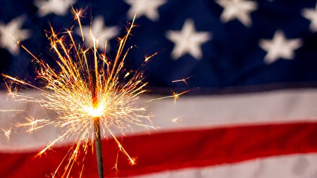Sparkler burning in front of the American flag, symbolizing patriotism and celebration