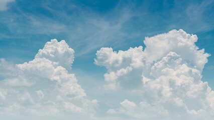 Fototapeta premium Panorama of fluffy white cumulus clouds on a clear blue sky, bright and airy natural background