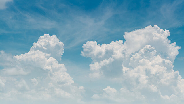 Panorama of fluffy white cumulus clouds on a clear blue sky, bright and airy natural background