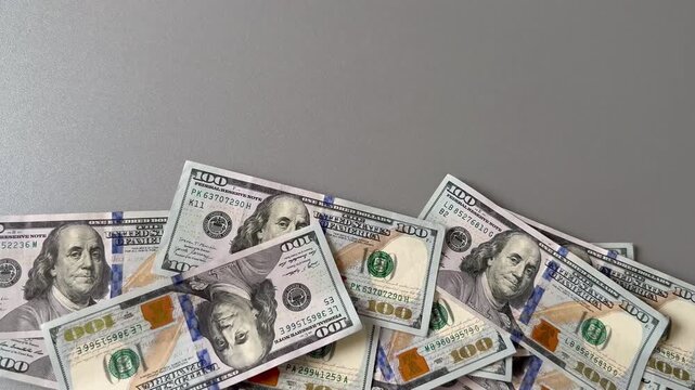 Close-up of one hundred dollar bills falling onto a pile of US currency. Concept of wealth, rain of money, financial success, economic growth, and big profit.