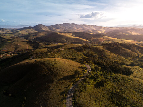 Drone capturando estrada sinuosa entre morros da Serra da Mantiqueira.
