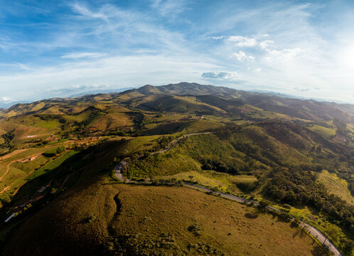 Estrada em curvas atravessando montanhas verdes na Mantiqueira, Minas Gerais.