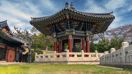 Naklejka premium Traditional Korean bell pavilion with colorful roof art and spring cherry blossoms