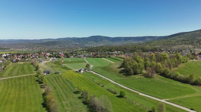 Aerial view of a valley town with meadows fields and forested mountains in the distance in Poland in spring