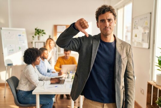 Man showing a thumbs down sign at the office, representing rejection or negative feedback