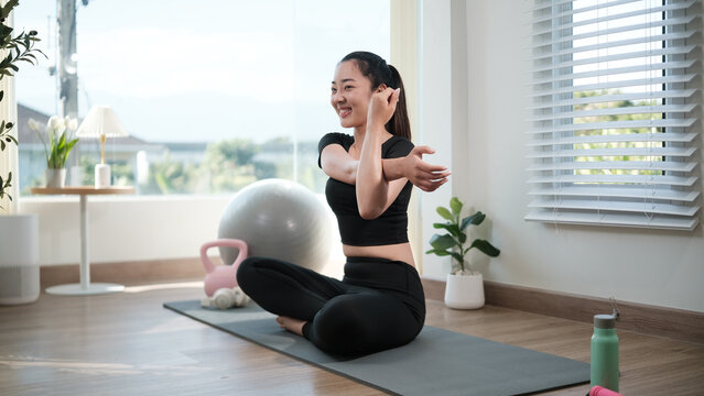 Young woman stretching her arm across the chest during a home workout. Healthy lifestyle concept.