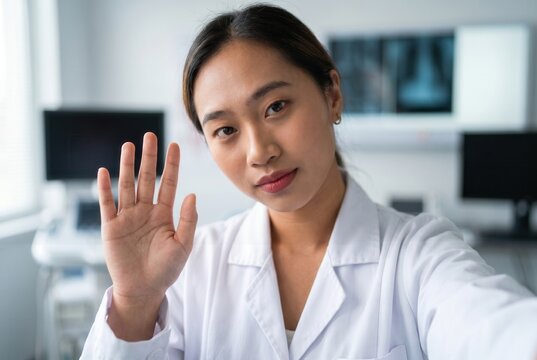 Young asian medic waving hand, communicating in online video consultation