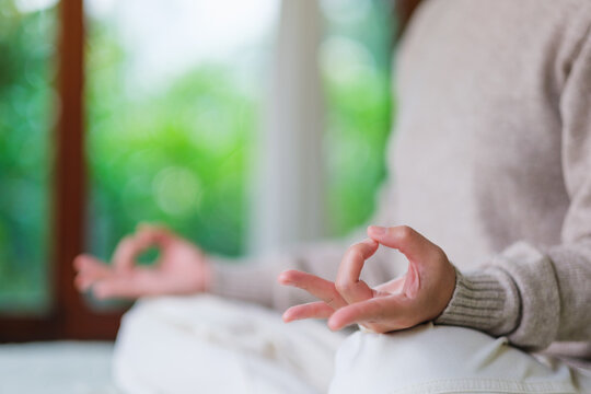 Closeup of a woman meditating or practicing yoga in lotus pose on the bed