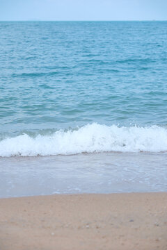 Vertical landscape image of white beach and sea wave
