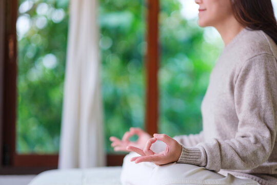 Closeup of a woman meditating or practicing yoga in lotus pose on the bed
