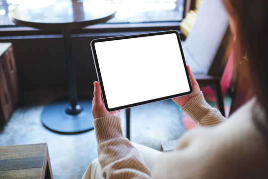 Mockup image of a woman holding digital tablet with blank white desktop screen in cafe
