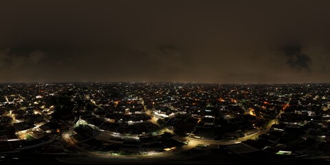 Wide panoramic aerial night view of a glowing city skyline with dense residential housing and a lit mosque minaret. © ahmadiliandy
