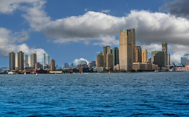 Obraz premium New york, usa august 16,2024. Manhattan skyline of new york city with towering skyscrapers along the hudson river on a cloudy day, panoramic waterfront view