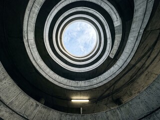 Fototapeta premium Beautiful Spiral Parking Garage Ramp from Below, Brutalist Concrete Geometry with Radial Perspective 