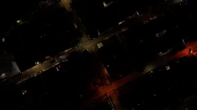 Top down aerial view of a dark intersection at night with orange street lights and minimal traffic.