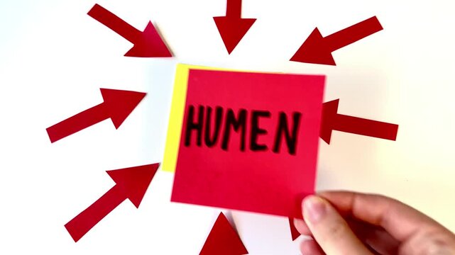 Hand places sticky note with 'AI' and 'HUMAN' labels. Red arrows point inward, showing interaction between AI and human. Visual suggests focus on technology's impact on people