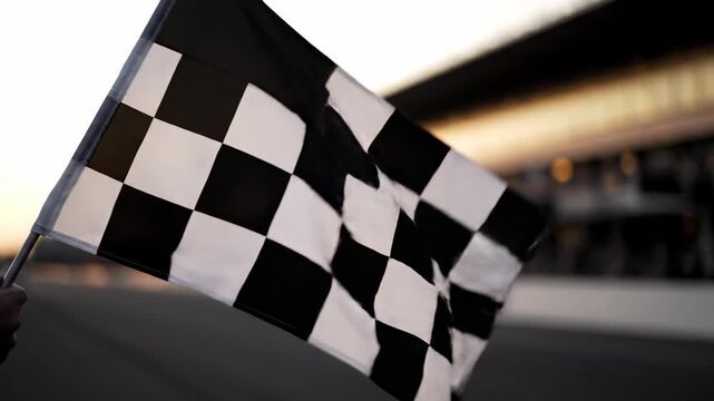 Close-up of checkered flag waving, at race track. Evening light in the background